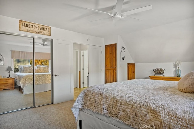 bedroom with light carpet, a ceiling fan, vaulted ceiling, and two closets