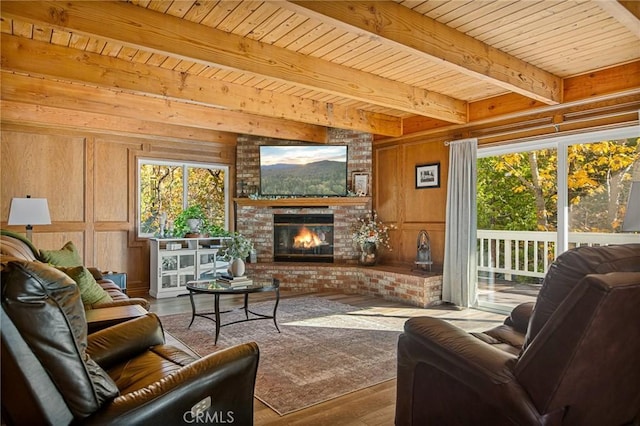 living area featuring a fireplace, wood walls, wood finished floors, wooden ceiling, and beamed ceiling