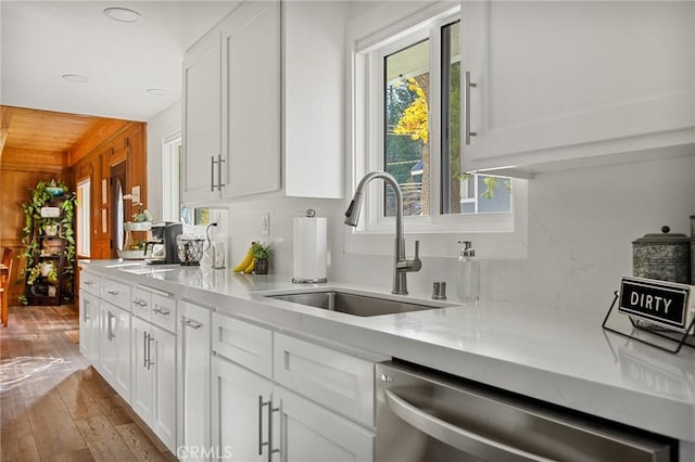 kitchen featuring dishwasher, light wood-style floors, a sink, and white cabinets