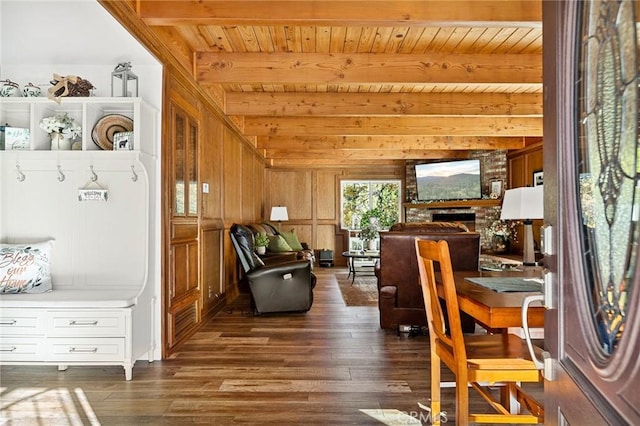 living area featuring dark wood-style floors, beam ceiling, a fireplace, wood ceiling, and wood walls