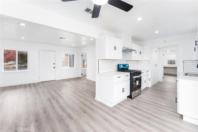 kitchen featuring backsplash, ceiling fan, light wood-type flooring, white cabinetry, and stainless steel range with gas stovetop