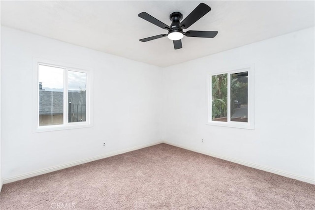 carpeted spare room featuring ceiling fan and a healthy amount of sunlight