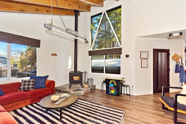 living room with beam ceiling, a wood stove, and light hardwood / wood-style floors