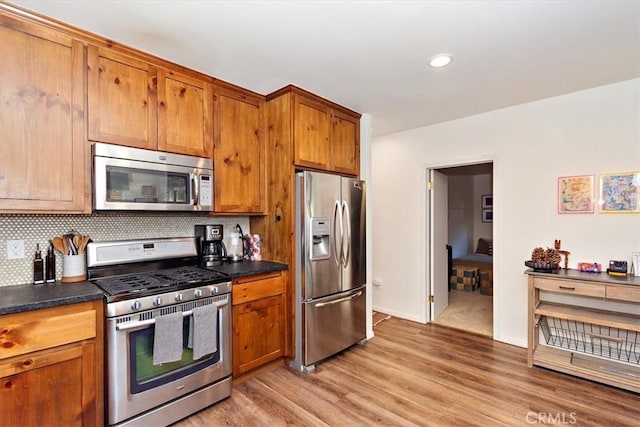 kitchen featuring decorative backsplash, appliances with stainless steel finishes, and light hardwood / wood-style flooring
