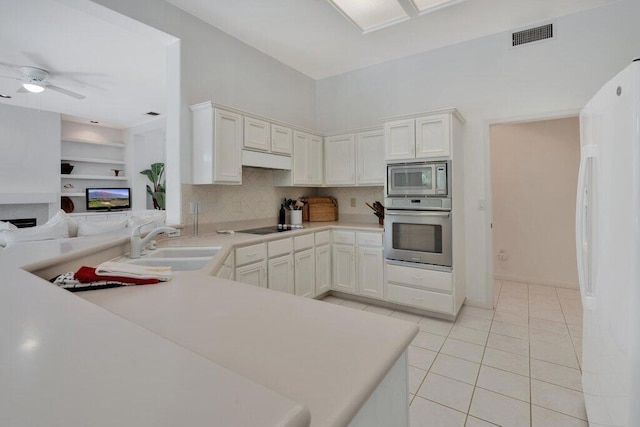 kitchen featuring ceiling fan, kitchen peninsula, white cabinetry, stainless steel appliances, and light tile patterned floors