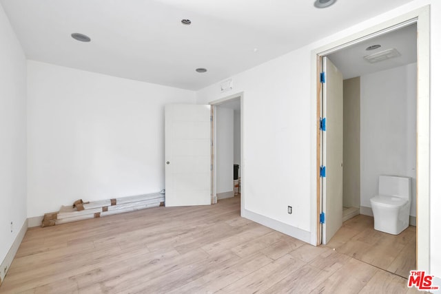 unfurnished bedroom with ensuite bathroom and light wood-type flooring