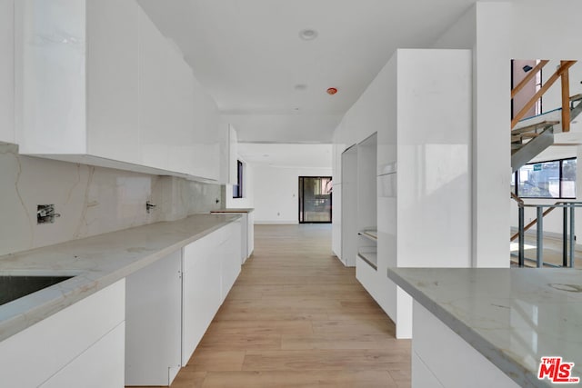 kitchen featuring white cabinets, light stone countertops, and light hardwood / wood-style flooring