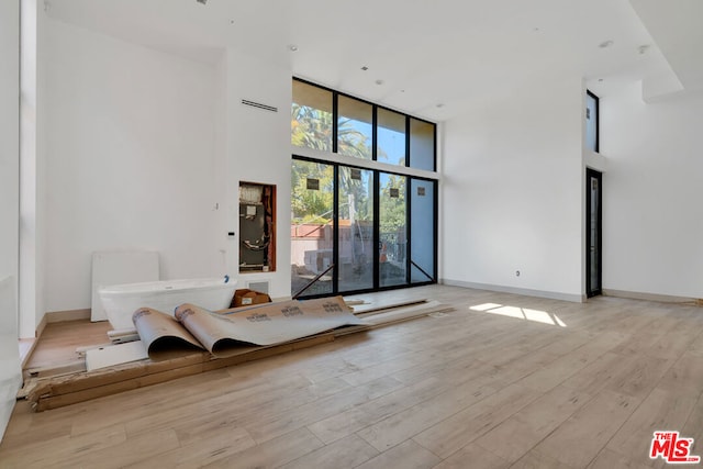 unfurnished living room featuring a high ceiling and light wood-type flooring