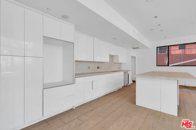 kitchen featuring tasteful backsplash, white cabinetry, a kitchen island, and light hardwood / wood-style floors