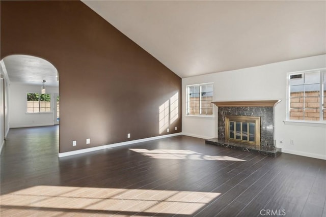 unfurnished living room featuring plenty of natural light, a fireplace, dark wood-type flooring, and high vaulted ceiling