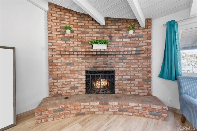 unfurnished living room featuring vaulted ceiling with beams, hardwood / wood-style floors, and a brick fireplace