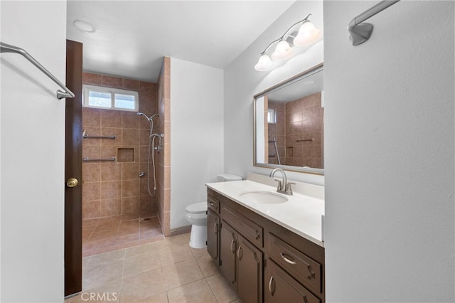 bathroom with tiled shower, vanity, toilet, and tile patterned flooring