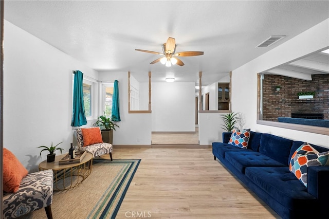 living room featuring ceiling fan, a textured ceiling, and light wood-type flooring