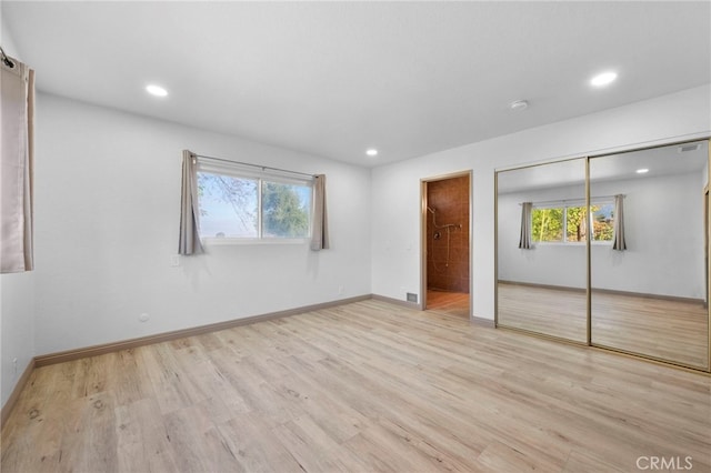 unfurnished bedroom featuring multiple windows, light hardwood / wood-style floors, and a closet