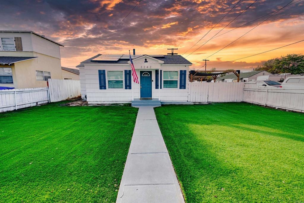 bungalow-style home with a lawn and solar panels