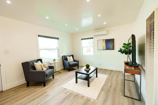 living area with a wall unit AC and light hardwood / wood-style floors