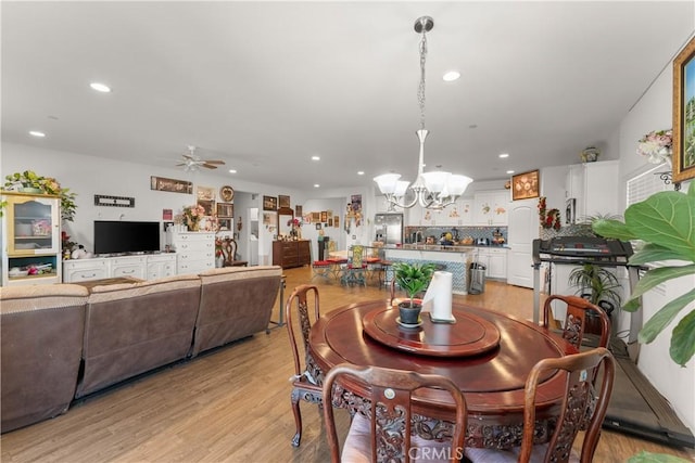 dining area featuring ceiling fan with notable chandelier and light hardwood / wood-style floors