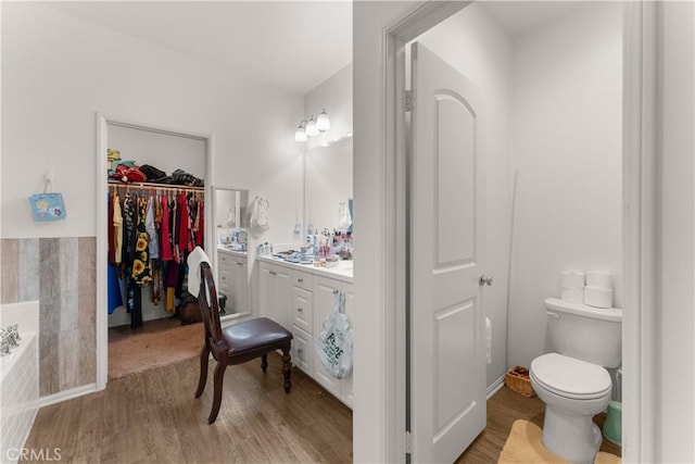 bathroom featuring a tub to relax in, vanity, hardwood / wood-style flooring, and toilet