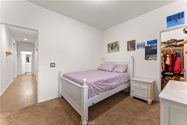 bedroom with a walk in closet, a closet, and light hardwood / wood-style flooring