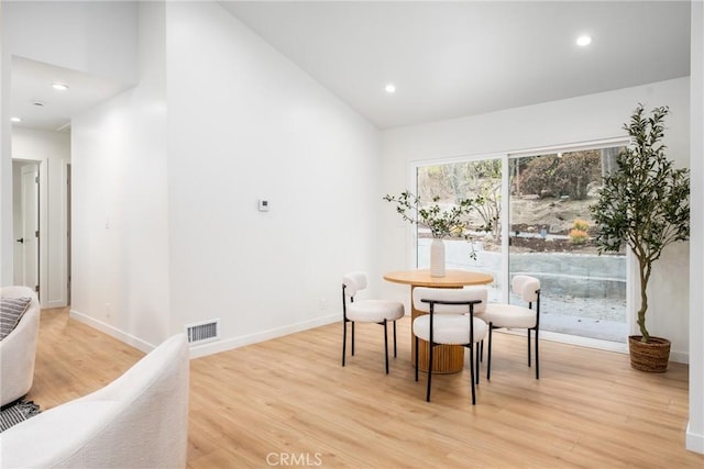 dining space with light hardwood / wood-style flooring and lofted ceiling