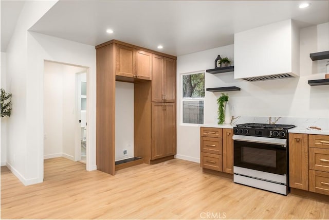 kitchen with white range with gas stovetop, light hardwood / wood-style flooring, and custom exhaust hood