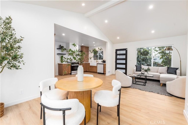 dining room featuring beam ceiling, light wood-type flooring, and high vaulted ceiling