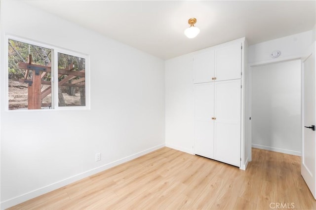 unfurnished bedroom with light hardwood / wood-style floors and a closet