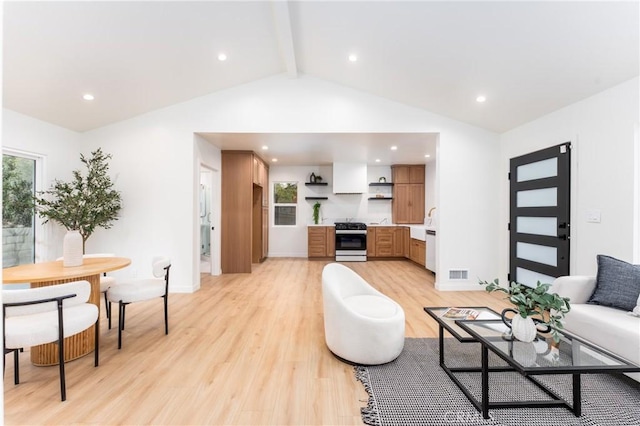 living room featuring lofted ceiling with beams and light hardwood / wood-style flooring