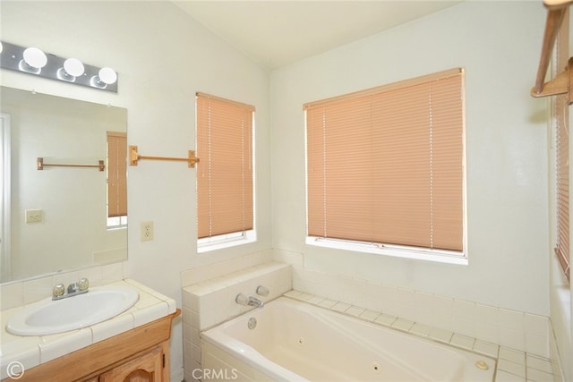 bathroom featuring lofted ceiling, a relaxing tiled tub, and vanity