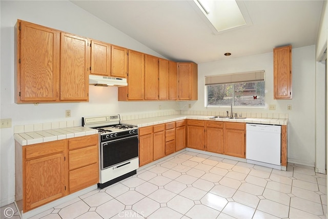 kitchen featuring sink, white appliances, tile counters, and vaulted ceiling