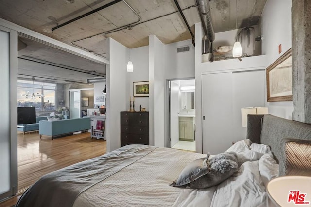 bedroom with wood-type flooring, ensuite bathroom, and a closet