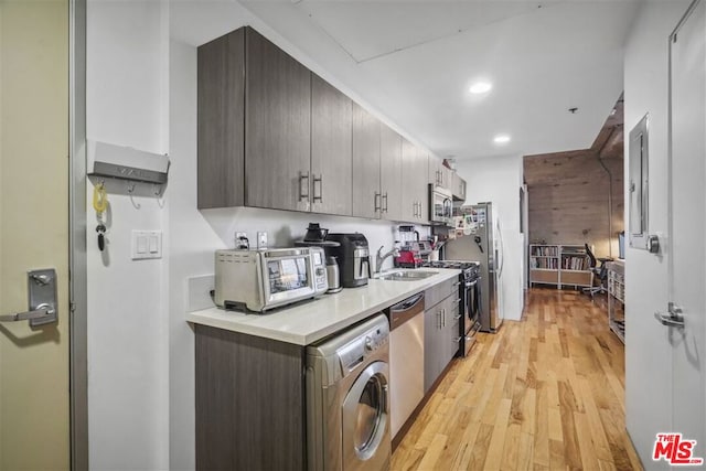 kitchen featuring stainless steel appliances, sink, light wood-type flooring, and washer / dryer