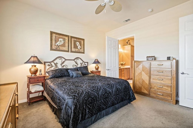 bedroom with ceiling fan, light colored carpet, and ensuite bath