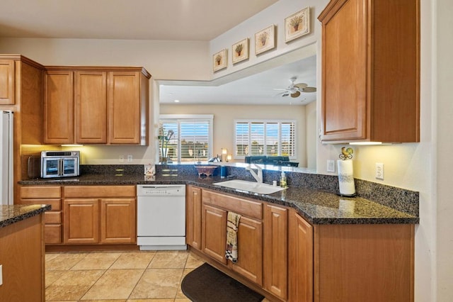 kitchen featuring sink, white appliances, light tile patterned floors, and dark stone countertops