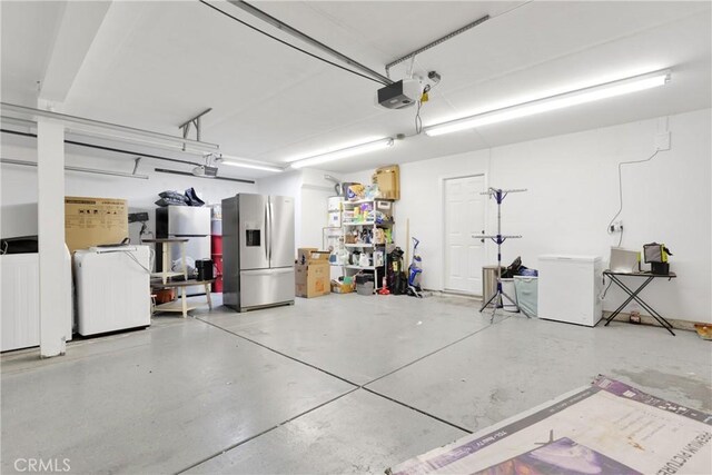 garage with fridge, a garage door opener, and stainless steel refrigerator with ice dispenser