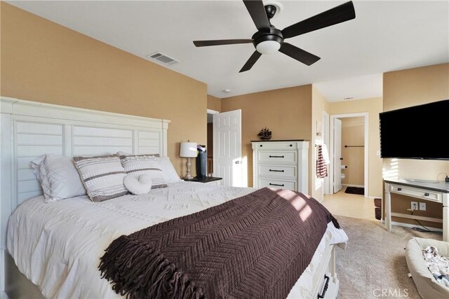 carpeted bedroom with ensuite bath and ceiling fan