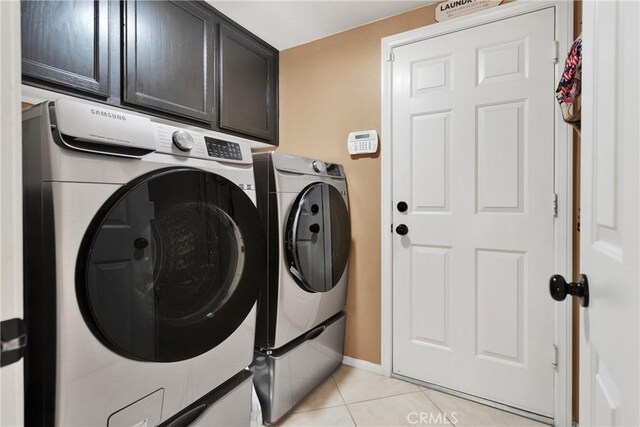 clothes washing area featuring cabinets, independent washer and dryer, and light tile patterned floors