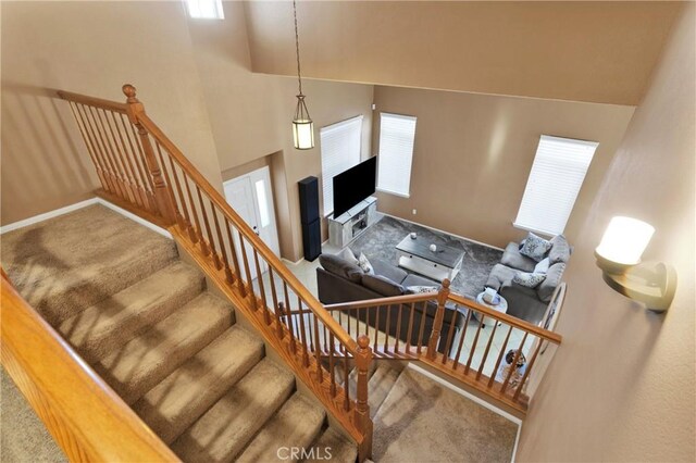 staircase with carpet, plenty of natural light, and a towering ceiling