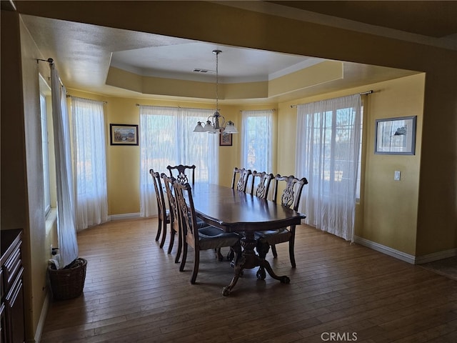 dining area featuring ornamental molding, hardwood / wood-style floors, a healthy amount of sunlight, and a notable chandelier