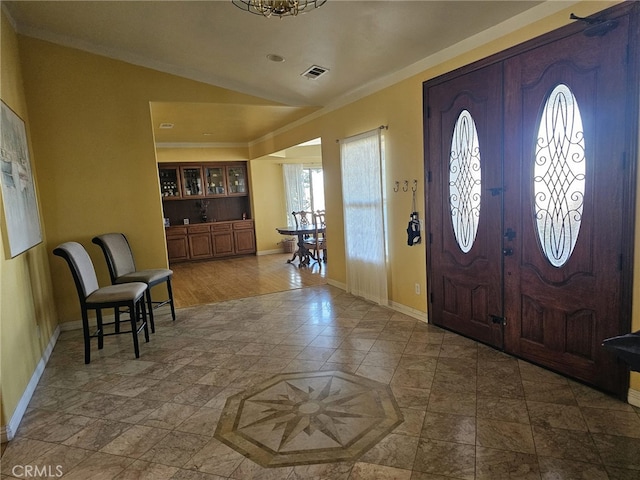 entrance foyer with hardwood / wood-style floors, ornamental molding, and vaulted ceiling