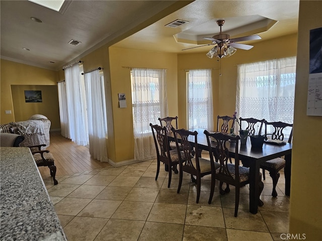 dining area featuring a raised ceiling, ceiling fan, hardwood / wood-style floors, and ornamental molding