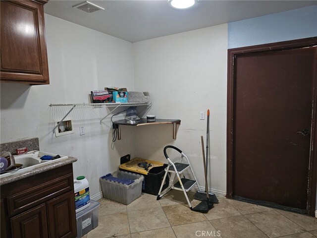 clothes washing area with cabinets, hookup for a washing machine, and light tile patterned floors