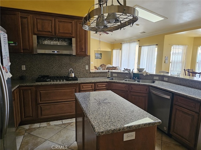 kitchen with a center island, sink, appliances with stainless steel finishes, tasteful backsplash, and extractor fan