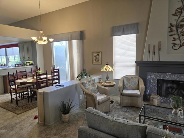 living room featuring a premium fireplace, lofted ceiling, and an inviting chandelier