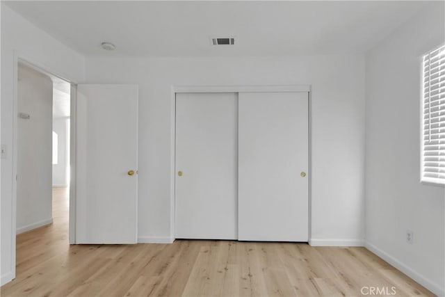 unfurnished bedroom with light hardwood / wood-style flooring and a closet