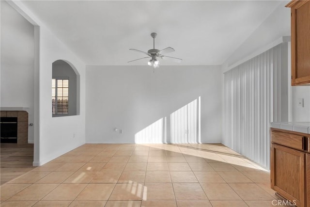 interior space featuring ceiling fan, light tile patterned floors, a fireplace, and lofted ceiling