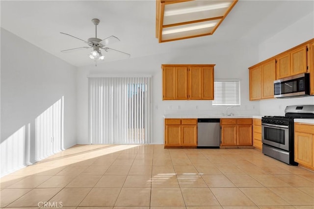 kitchen with ceiling fan, light tile patterned floors, stainless steel appliances, and vaulted ceiling