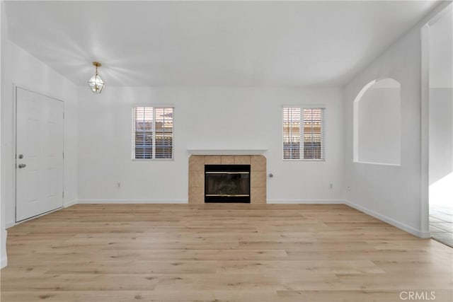 unfurnished living room with a wealth of natural light, a fireplace, and light wood-type flooring