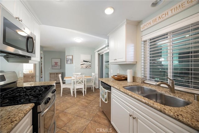 kitchen featuring sink, appliances with stainless steel finishes, light tile patterned flooring, light stone counters, and white cabinetry