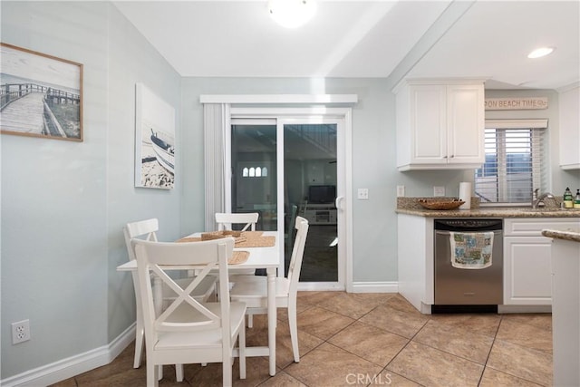 kitchen featuring white cabinets, light tile patterned floors, stainless steel dishwasher, and sink